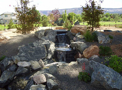 Residential landscaping water feature with rocks and waterfall installed by Painted Desert Landscaping